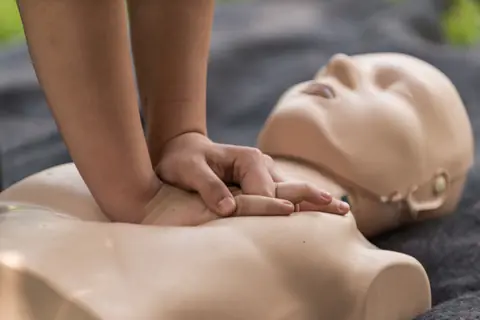 A trainee practising CPR on a first aid manikin