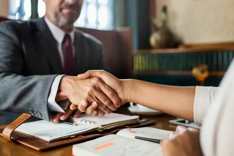 Two professionals shaking hands across a desk